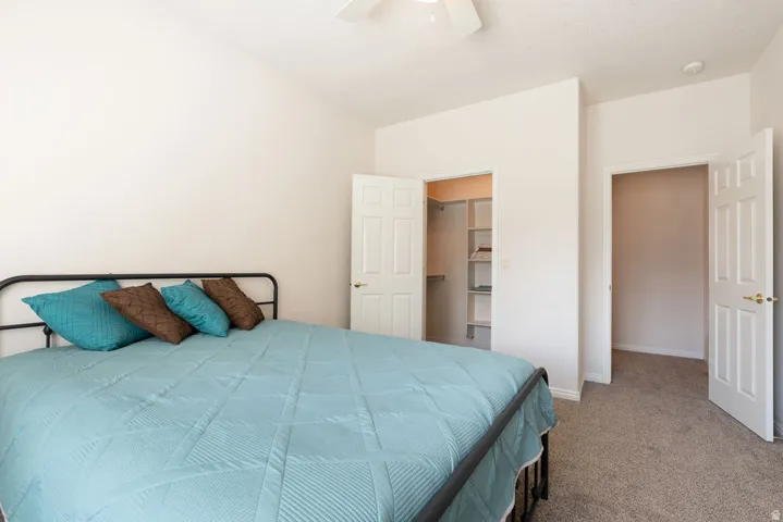 Vaulted ceiling with a ceiling fan, carpeted flooring, and two interior doors