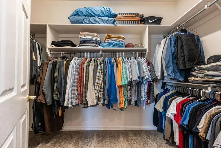 Walk-in closet featuring built-in shelving, multiple hanging rods, and carpet flooring