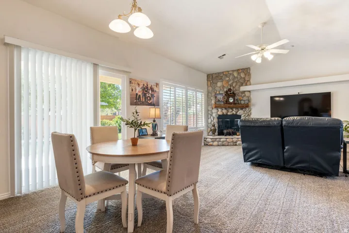 Spacious room with a vaulted ceiling, stone-surround fireplace, and a ceiling fan