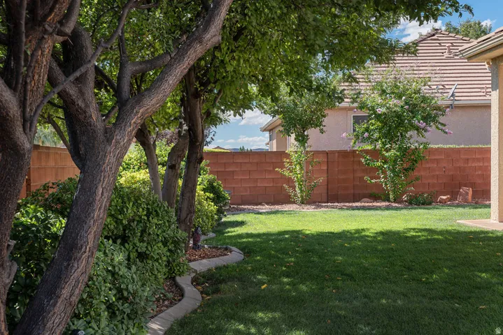 Expansive green lawn with mature trees and established shrubbery, complemented by a block wall perimeter
