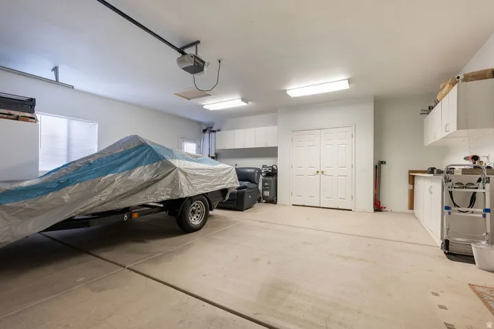 Attached white cabinetry, recessed fluorescent lighting, light-toned concrete flooring, double panel doors, and a built-in workbench