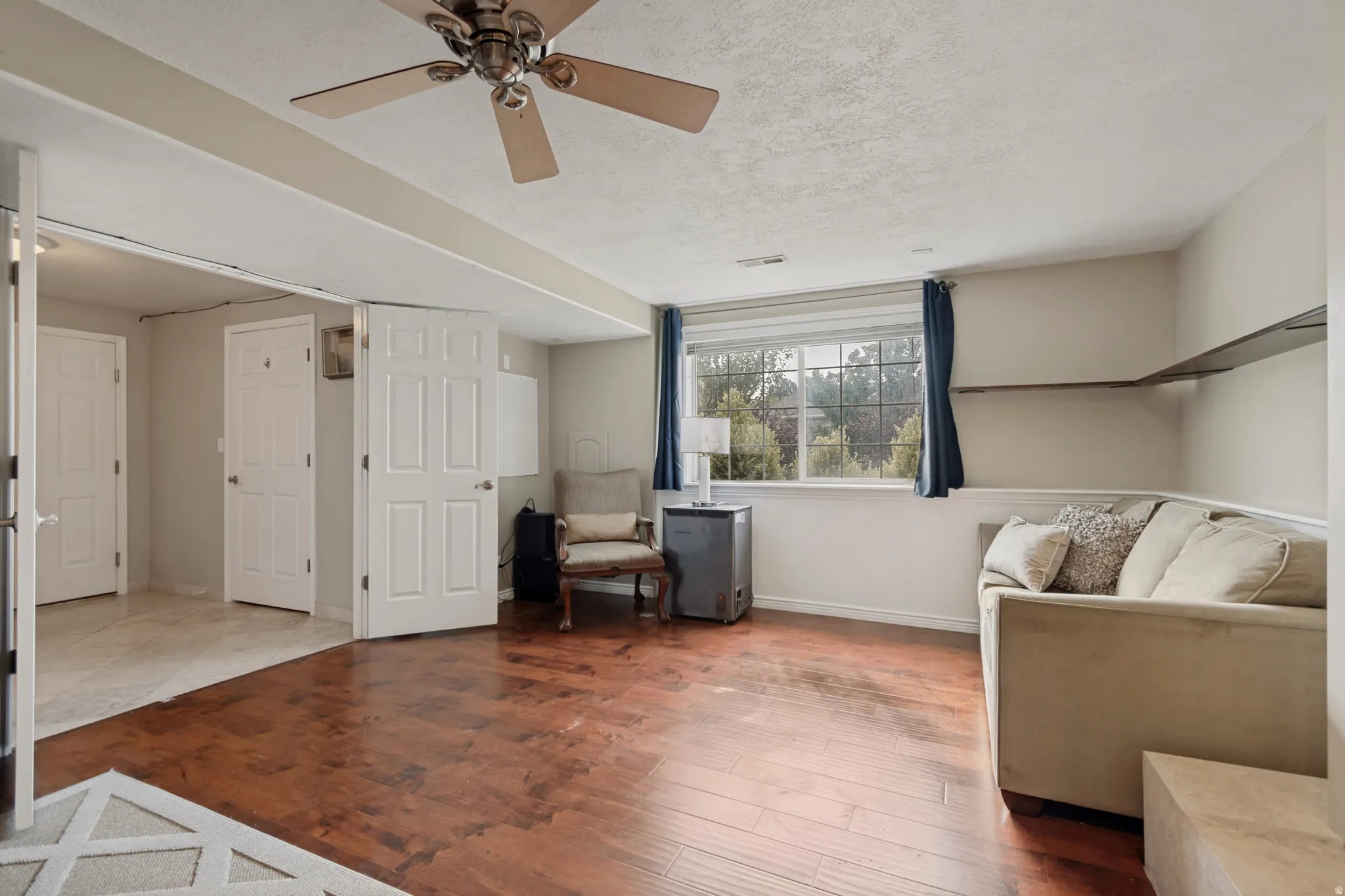 Hardwood-style flooring, a ceiling fan, baseboard trim, and a window with exterior scenery