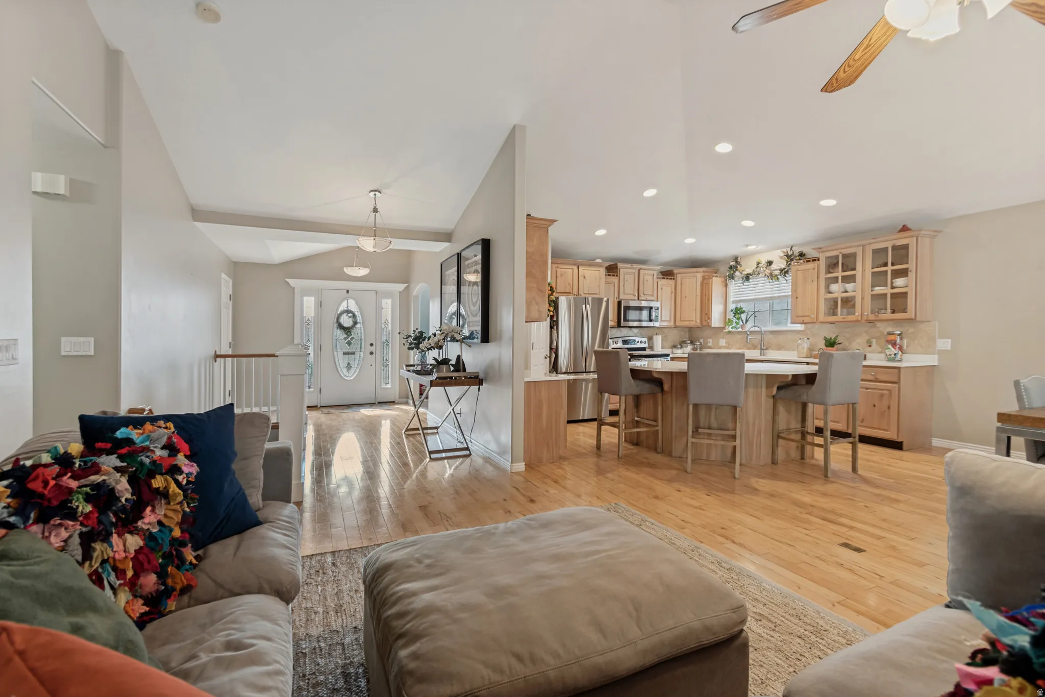 Vaulted ceilings, wood-finish flooring, recessed lighting, and a kitchen island with seating