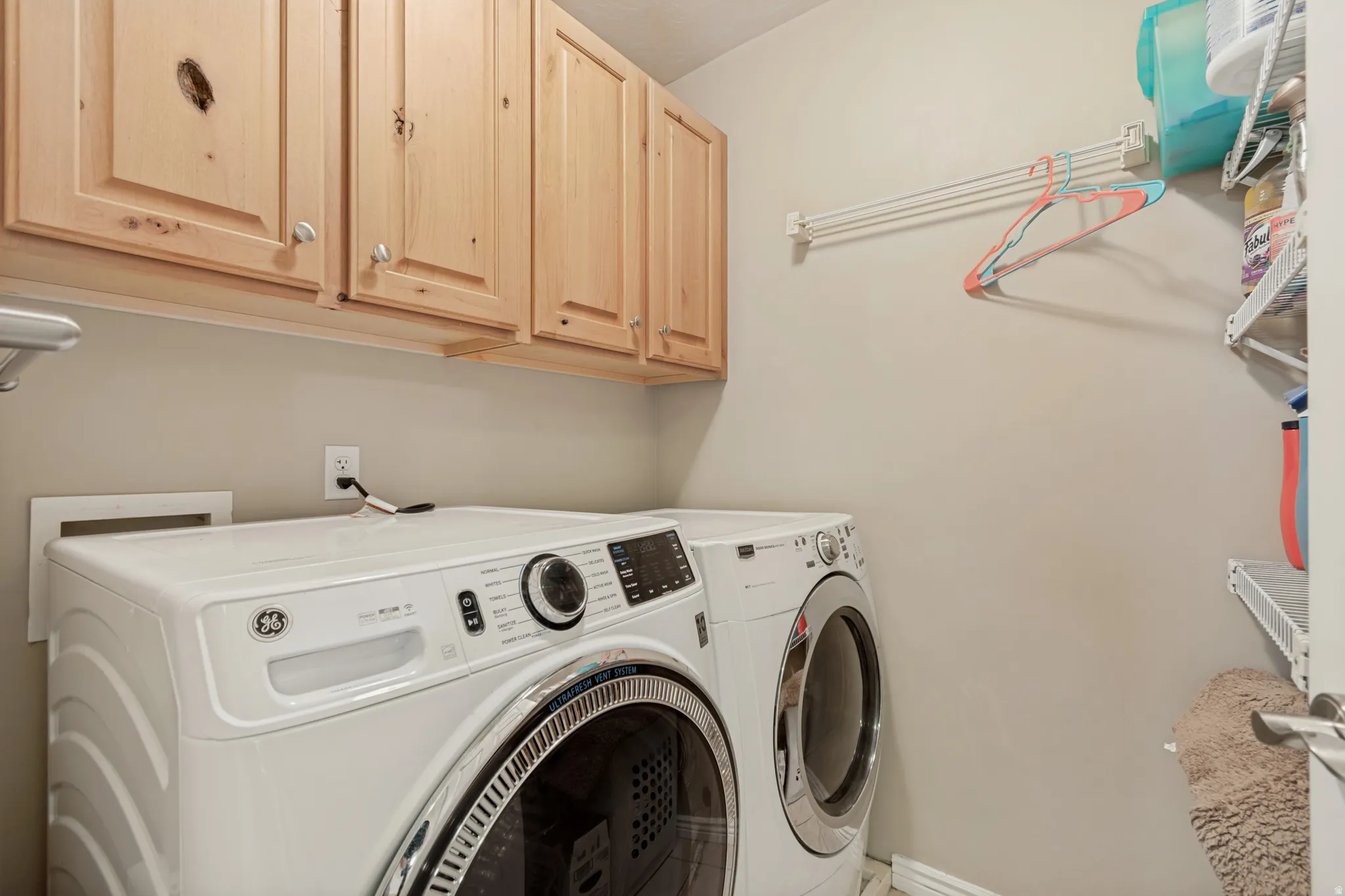 Built-in wooden cabinetry, white washer and dryer units, and wall-mounted shelving
