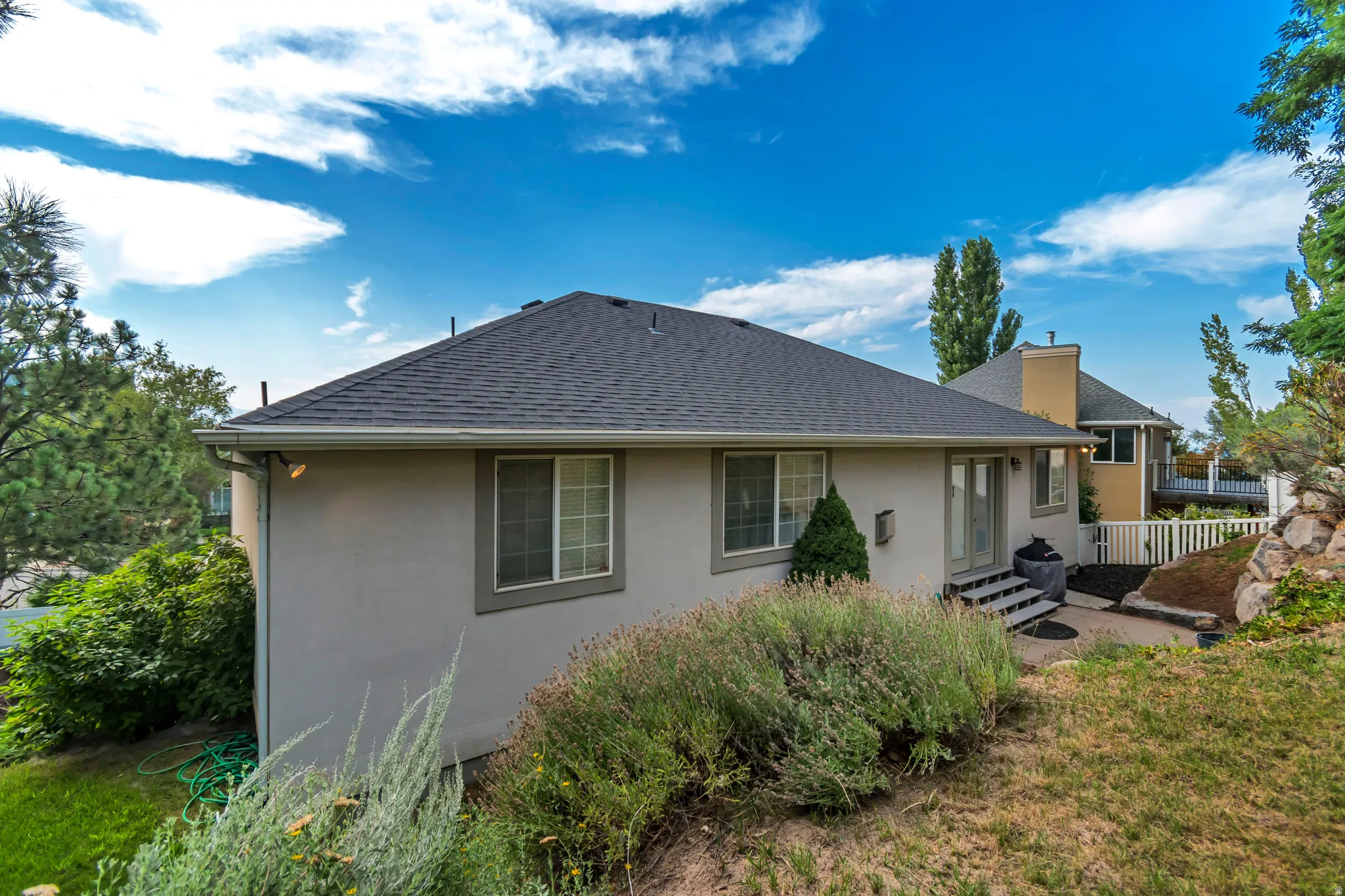 Stucco exterior with multiple windows, leading to a patio with stairs