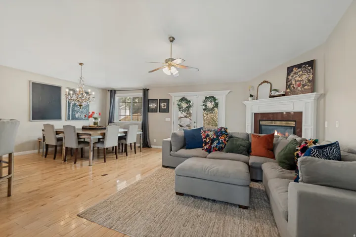Open concept living area featuring light wood-finish flooring, a chandelier, and a built-in fireplace with a white mantel