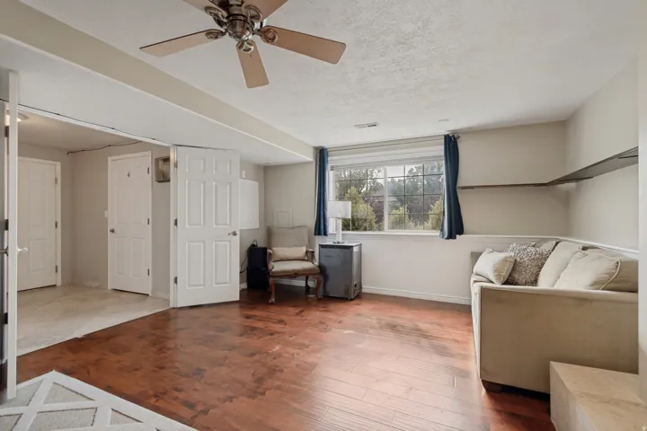 Hardwood-style flooring, a ceiling fan, baseboard trim, and a window with exterior scenery