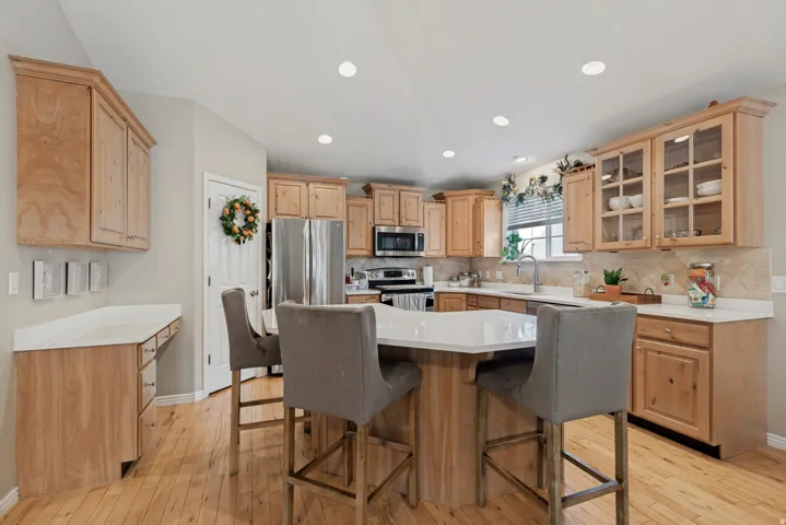Kitchen featuring wood-finish cabinetry, stainless steel appliances, a center island with seating, a window with blinds, and recessed lighting