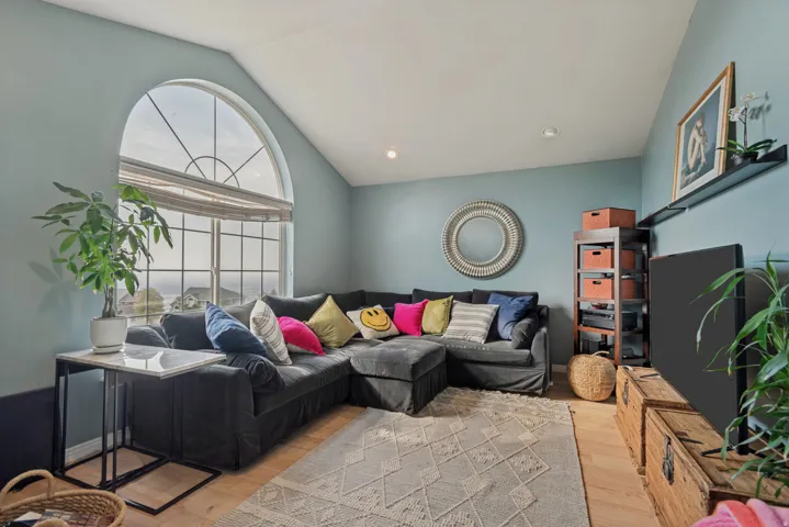 Arched picture window, vaulted ceiling, recessed lighting, wood-finish flooring, wall-mounted shelving