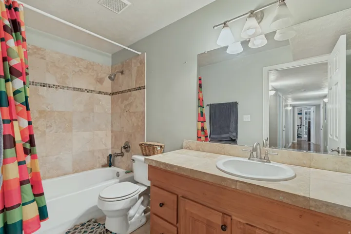 Bathtub with tile surround, wood-finish vanity with countertop, and integrated sink