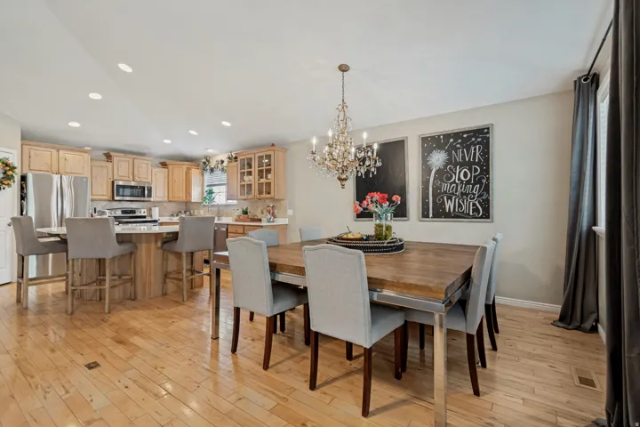 Open-concept living space with wood-finish flooring, recessed lighting, and a crystal chandelier
