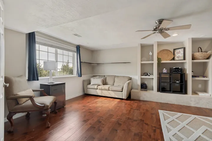 Hardwood-finish flooring, built-in shelving, ceiling fan, and large casement windows