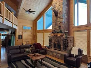 Vaulted wood-paneled ceiling, stone fireplace, upper-level balcony, and large windows with natural light