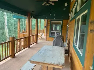 Expansive covered porch featuring wood railings, exposed wood support beams, and a ceiling fan