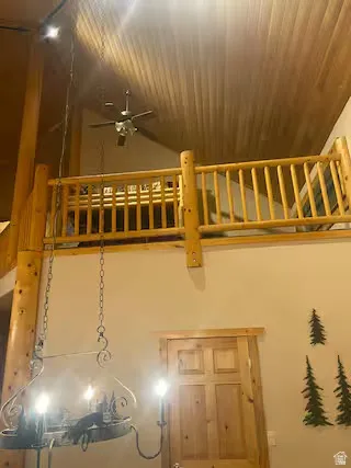 Vaulted wood-finish ceiling, wood-finish interior balcony railing, ceiling fan, and wood-panel door