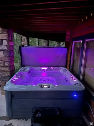 Spa with interior lighting, stone column, and exterior decking