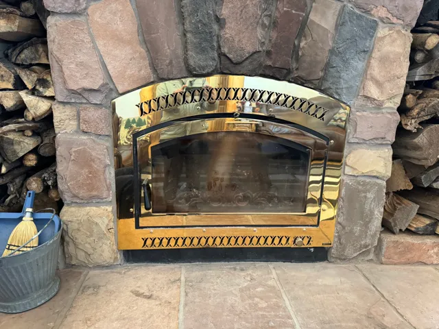 Stacked stone fireplace surround with a brass-finish insert