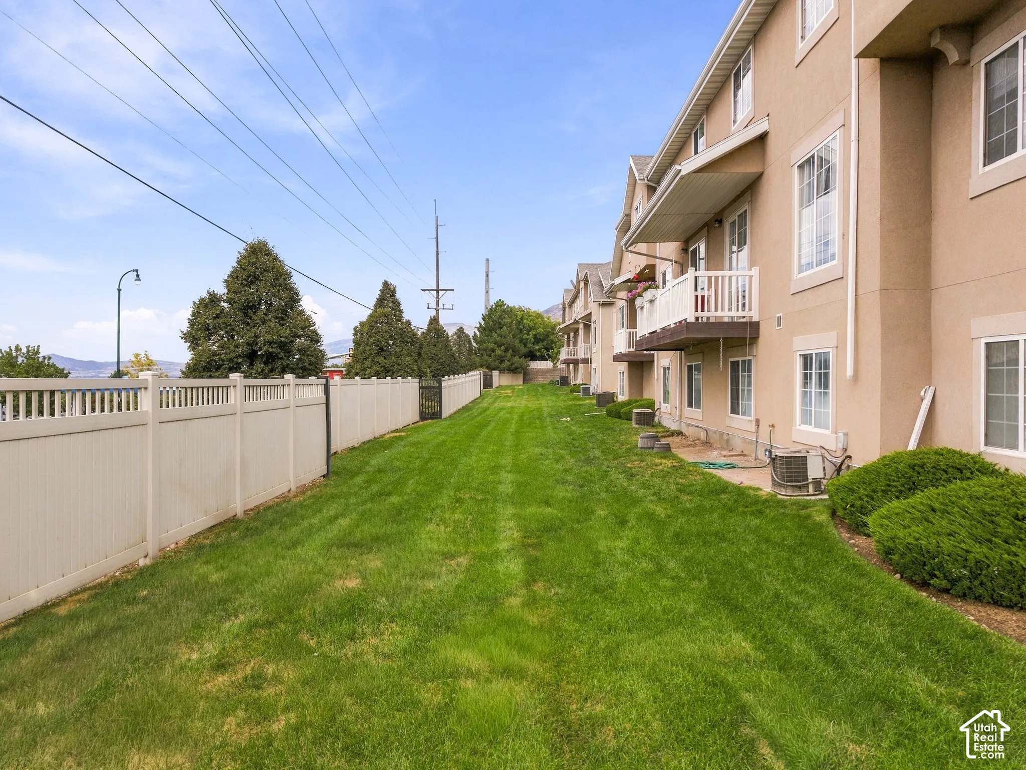 Expansive green space featuring a privacy fence, mature perimeter trees, and established shrubbery
