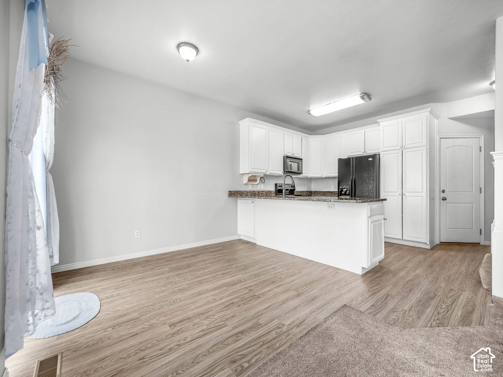 Kitchen area featuring white cabinetry, a built-in microwave, and wood-finish flooring
