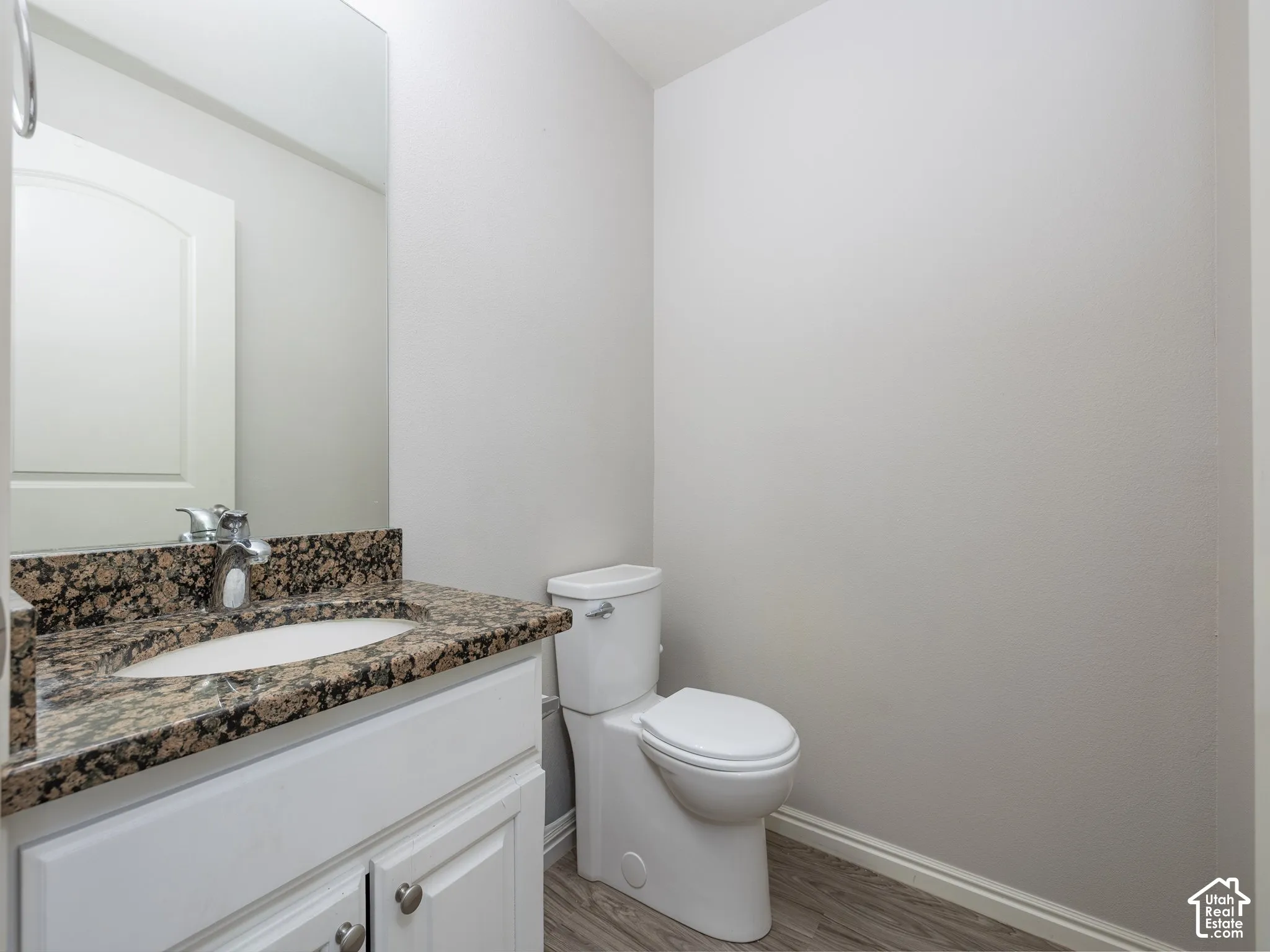 White vanity with a brown speckled countertop, an undermount sink, and a chrome faucet