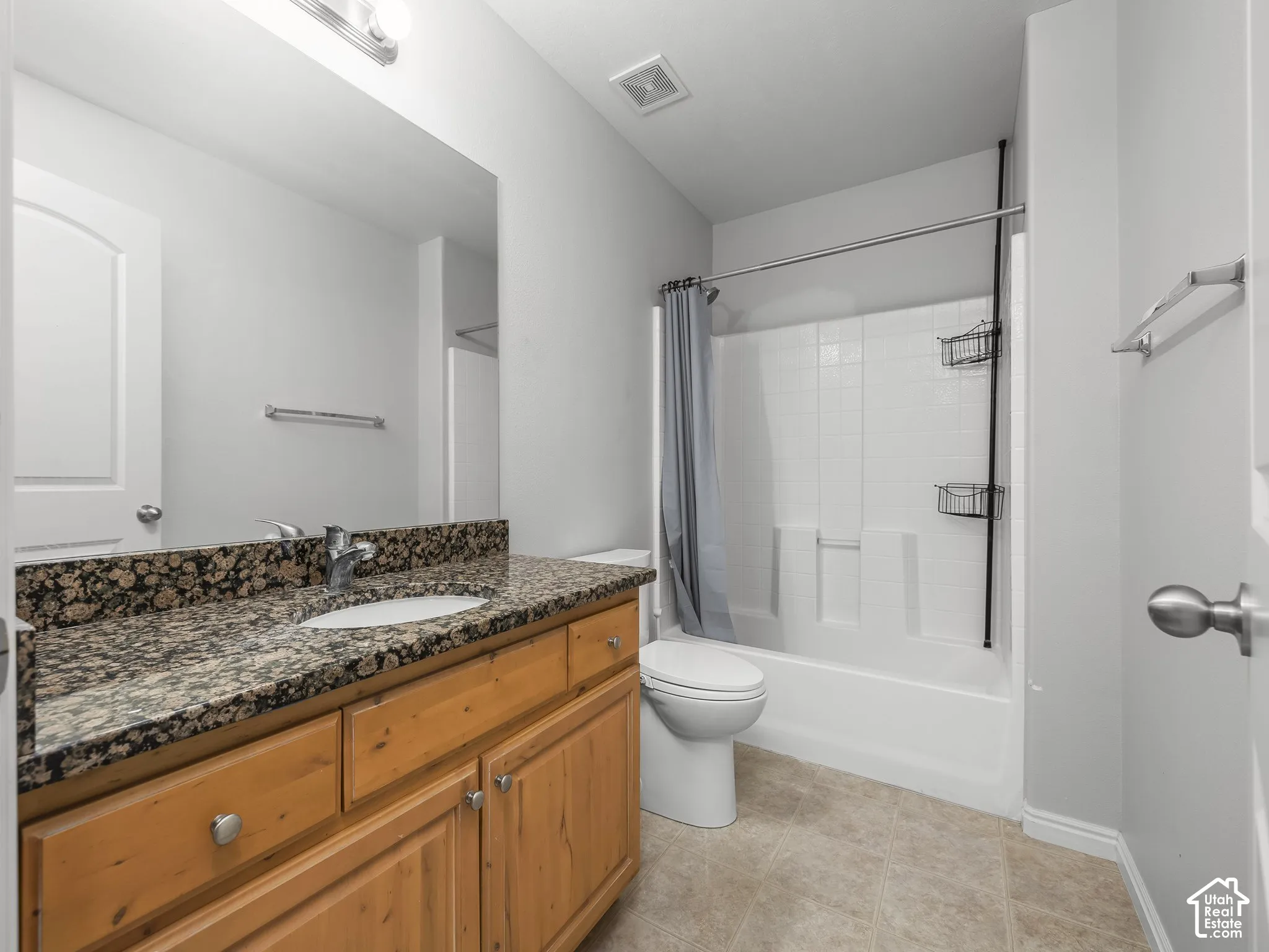 Granite-style countertop with an undermount sink, wood-finish cabinetry, and a full vanity mirror