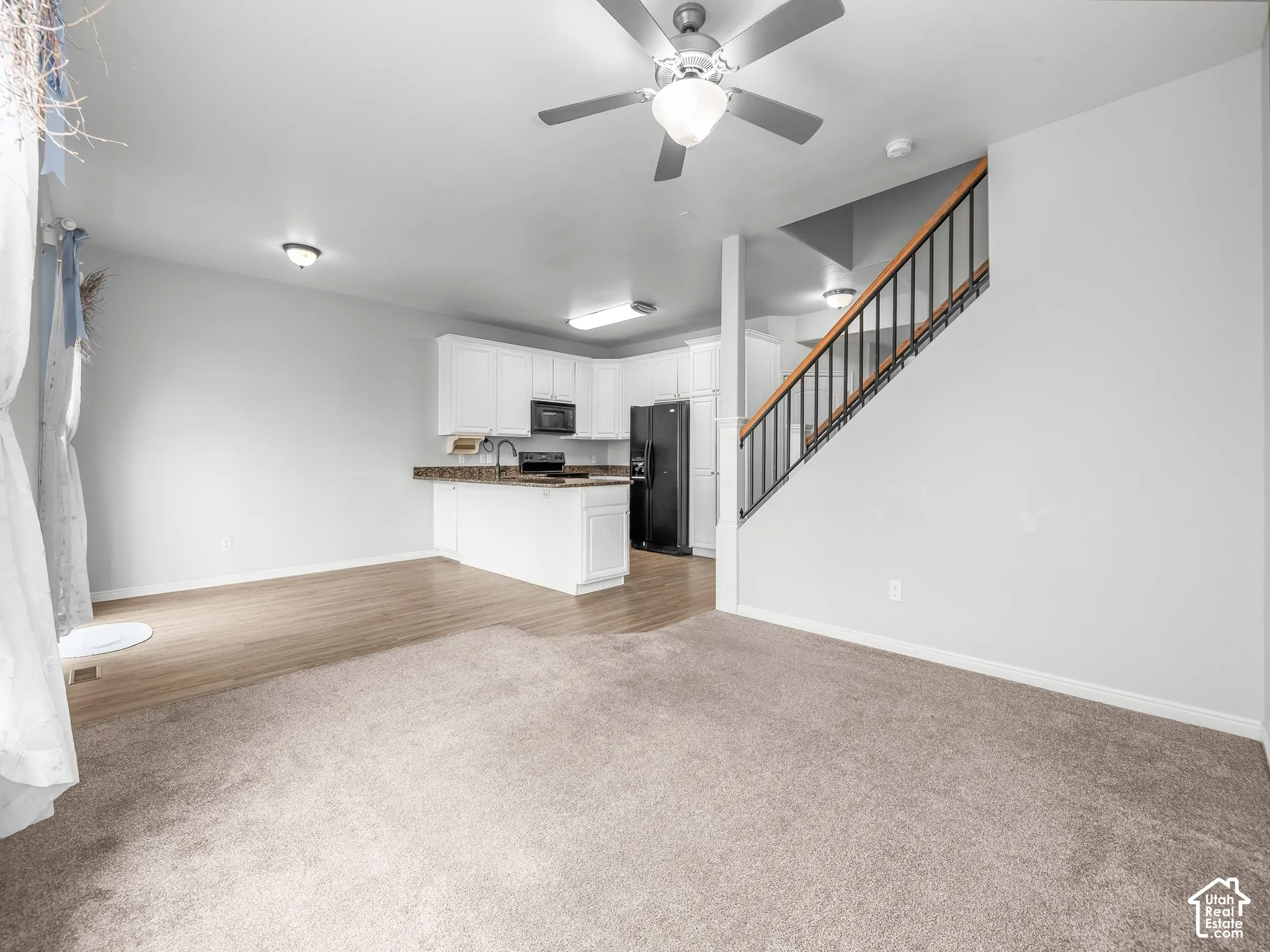 Open-concept living space with light-tone carpeting and wood-finish flooring