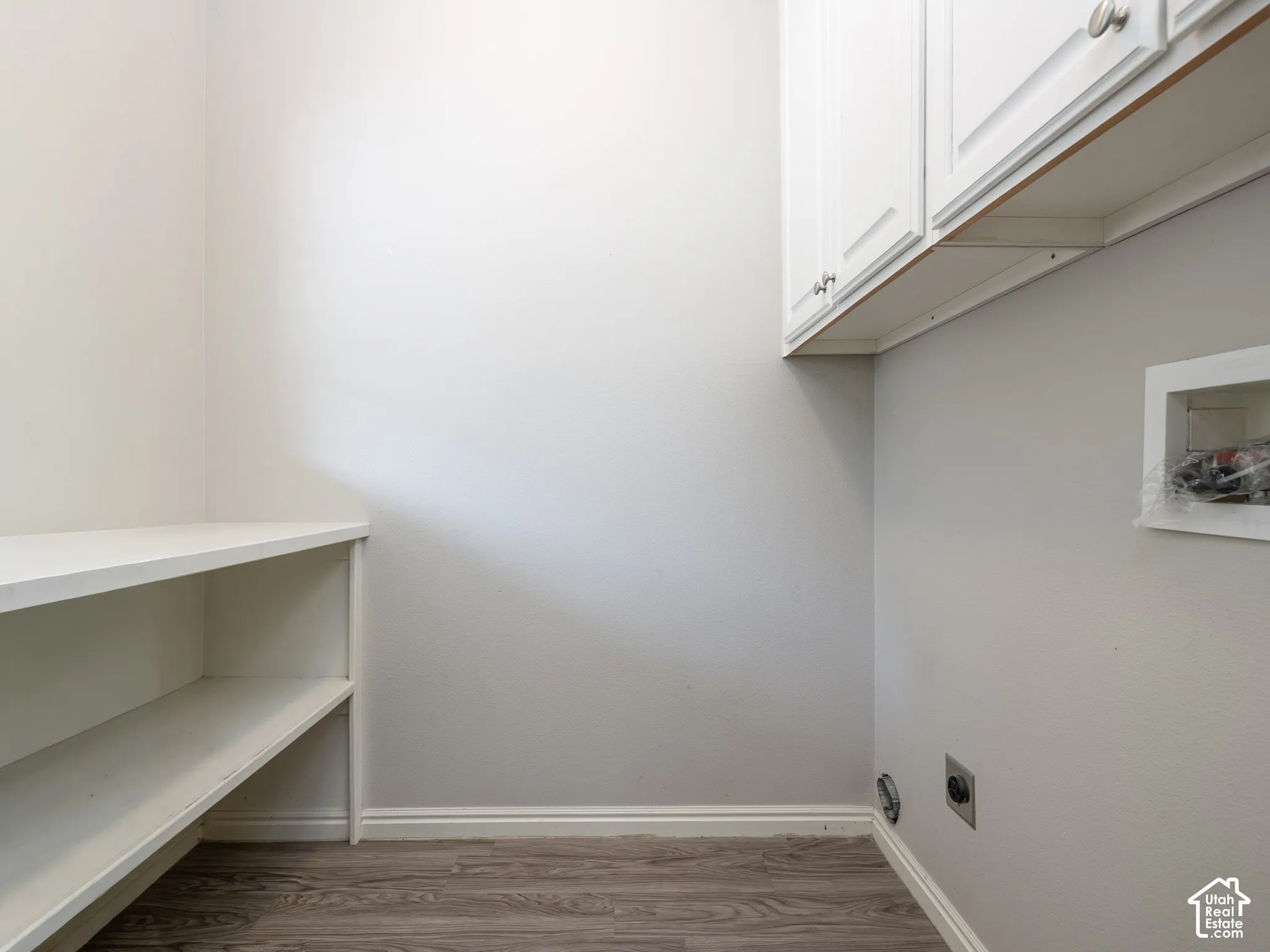 White shaker-style cabinetry with silver hardware, built-in shelving, and wood-finish flooring