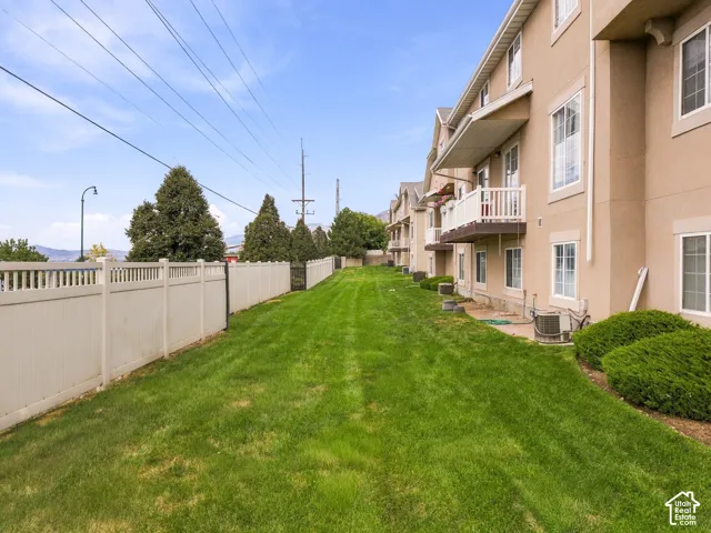 Expansive green space featuring a privacy fence, mature perimeter trees, and established shrubbery