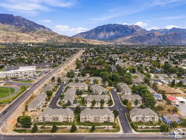 Residential development with multiple buildings featuring a neutral exterior and dark roofing, set against a mountainous backdrop