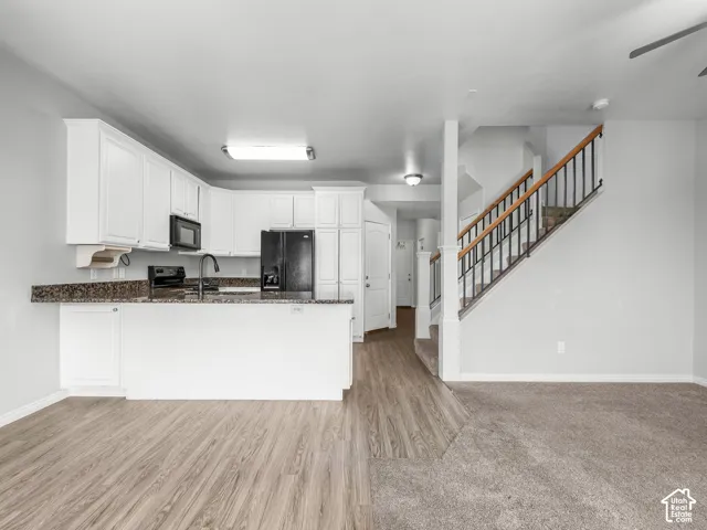 Kitchen featuring white cabinetry, dark stone-finish countertops, and a full suite of black appliances