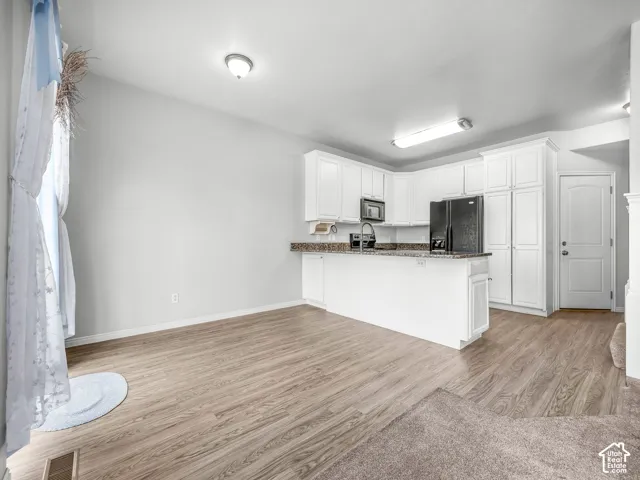 Kitchen area featuring white cabinetry, a built-in microwave, and wood-finish flooring