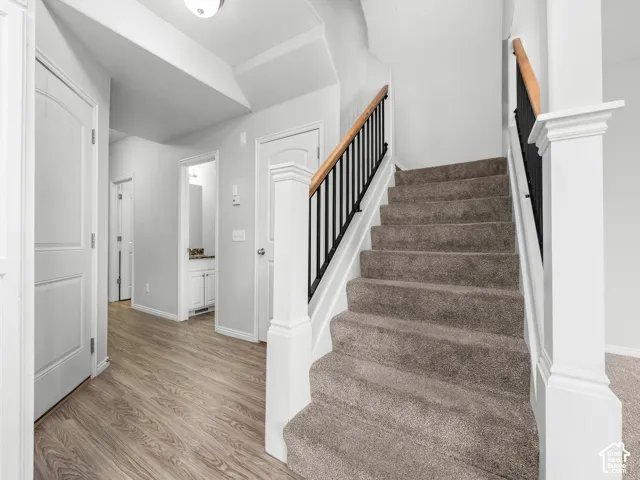 Carpeted staircase with dark iron balusters and wood-finish handrail