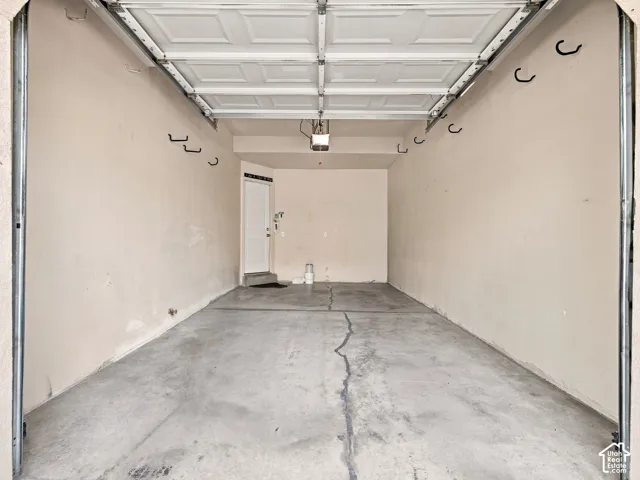 Attached garage with concrete flooring, interior access door, and overhead garage door mechanism