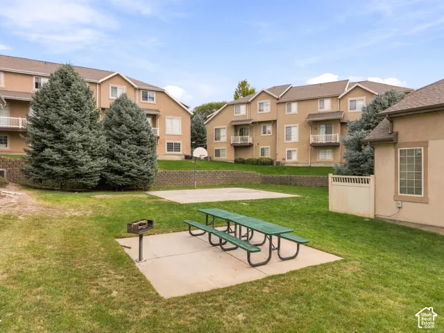 Expansive green lawn featuring a concrete patio with a picnic table and grill