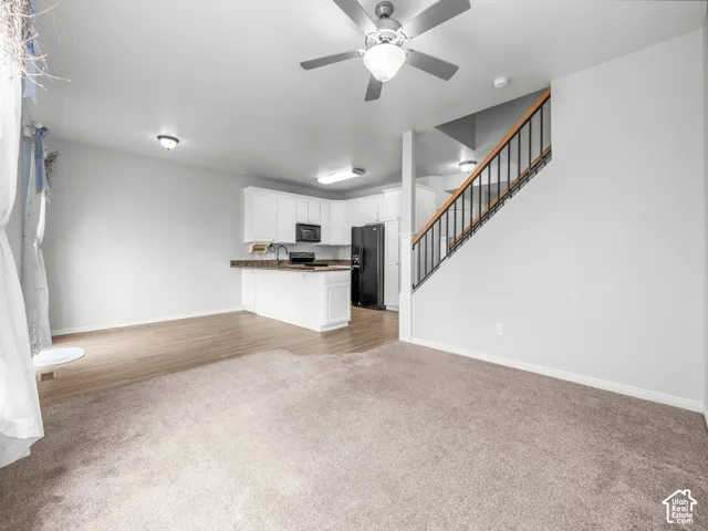 Open-concept living space with light-tone carpeting and wood-finish flooring