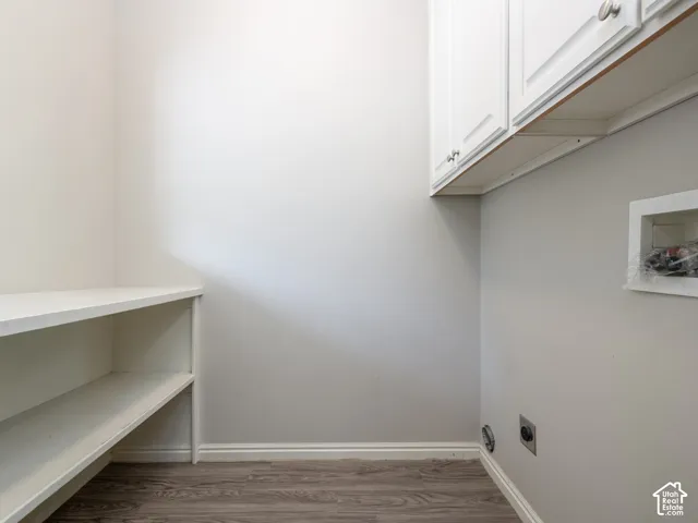 White shaker-style cabinetry with silver hardware, built-in shelving, and wood-finish flooring