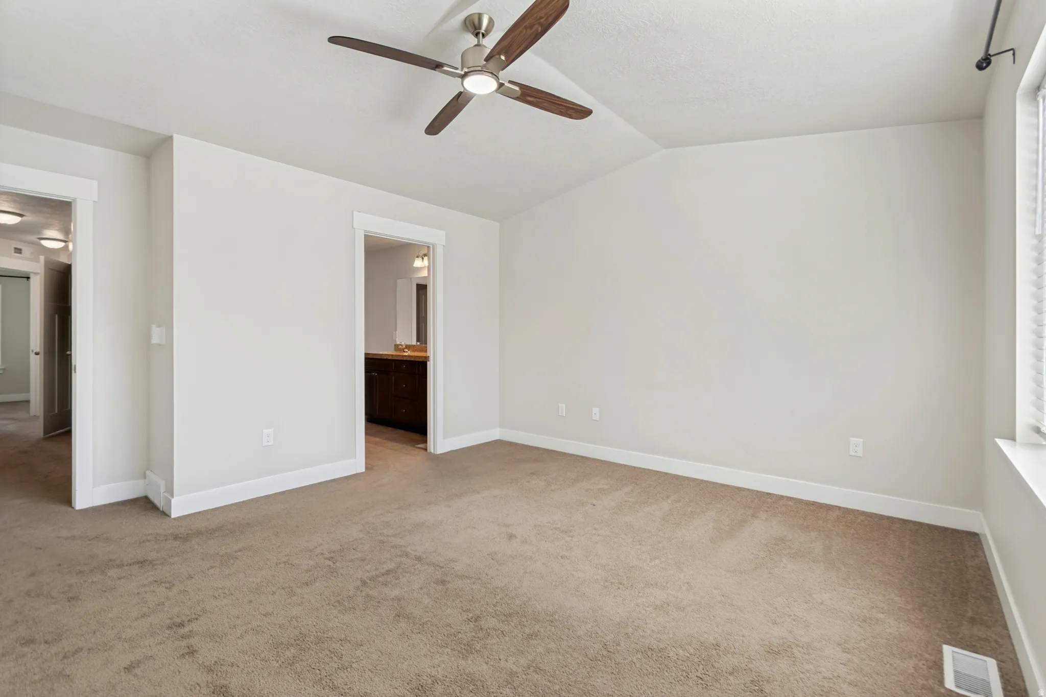 Spacious room featuring neutral carpet flooring, a ceiling fan with integrated lighting, and white trim