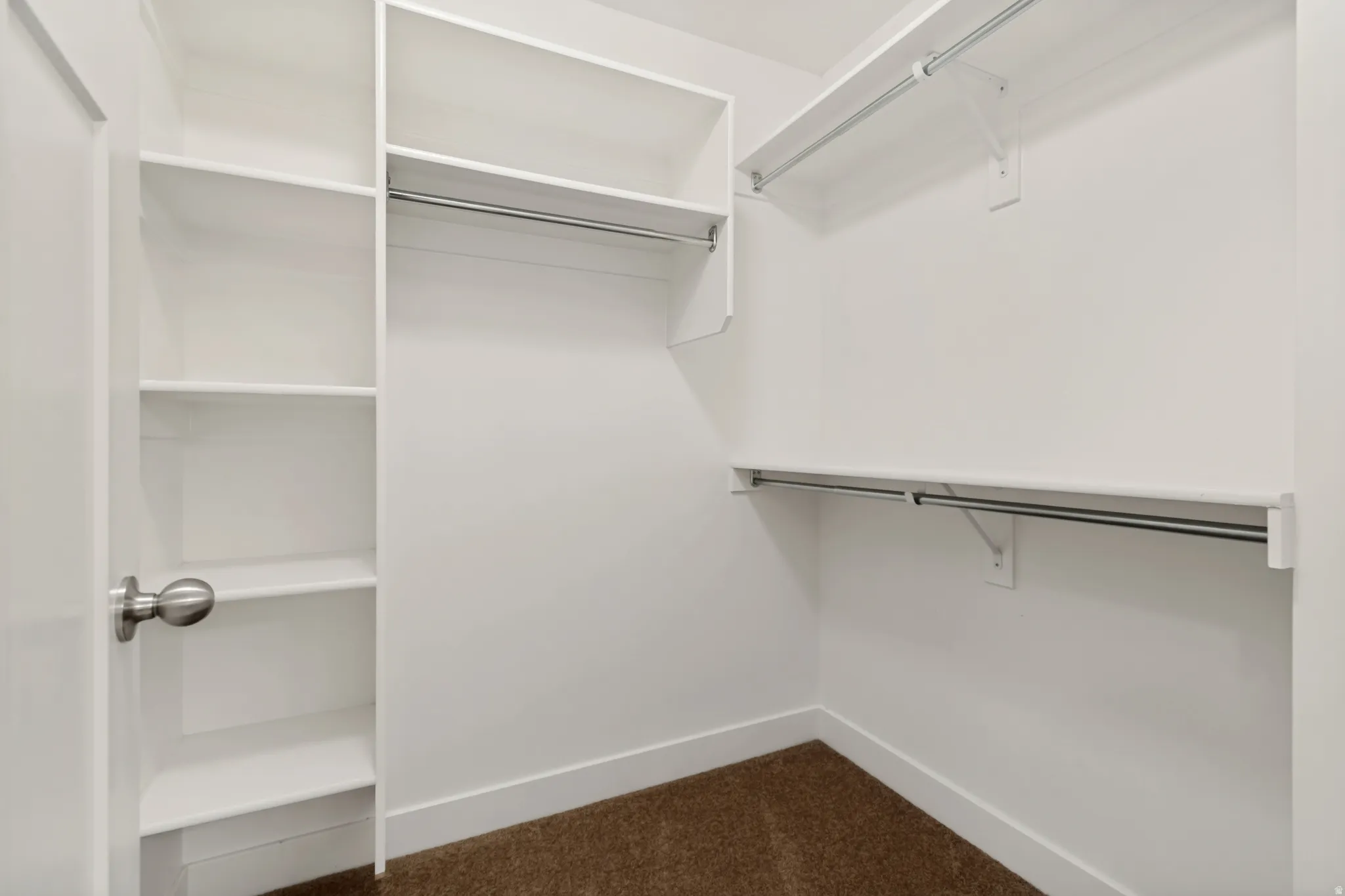 Built-in shelving, white walls, and a silver-toned doorknob complement the carpeted flooring