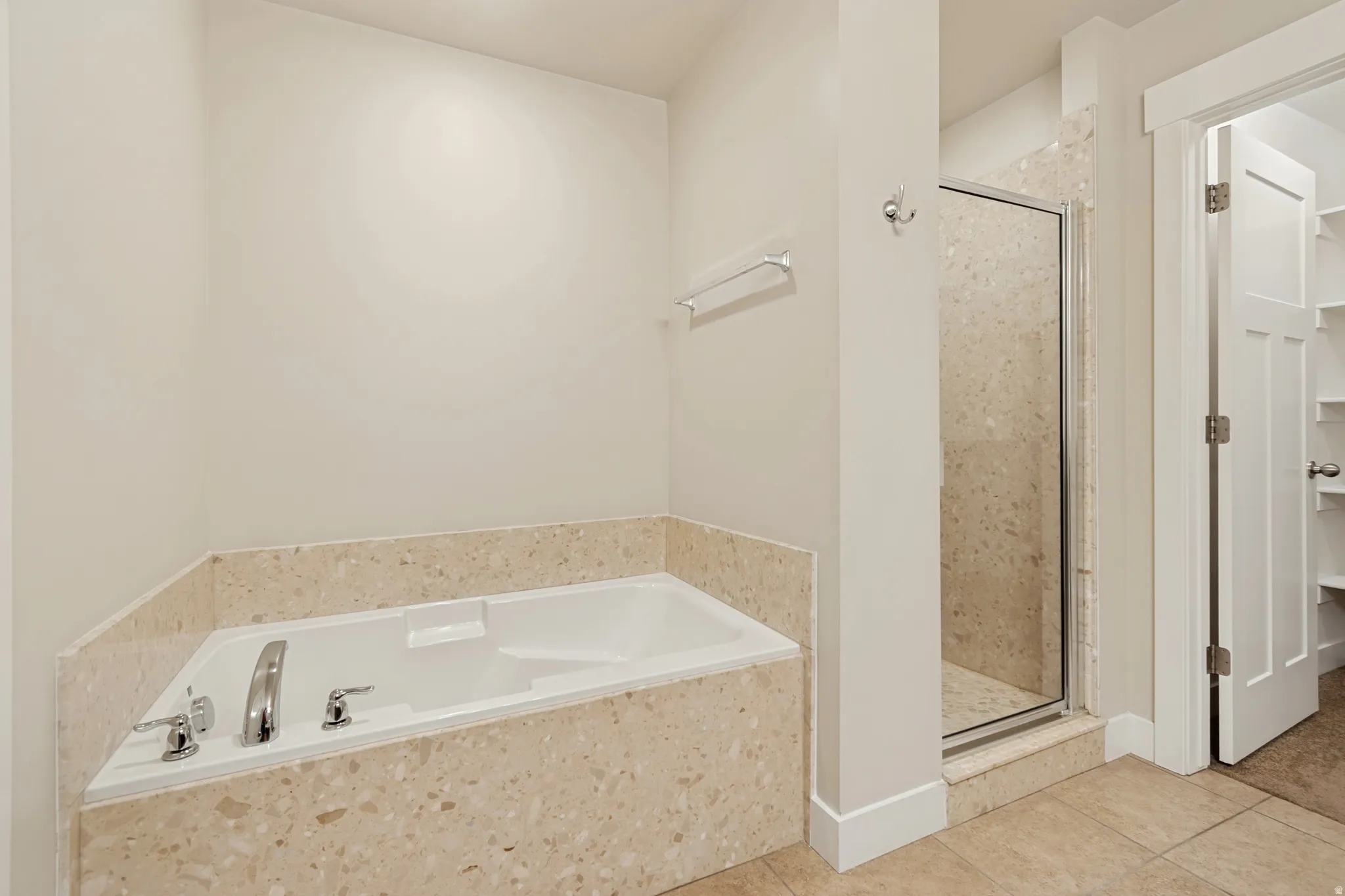 Built-in soaking tub with a tiled surround, chrome fixtures, and a glass-enclosed shower with tiled walls