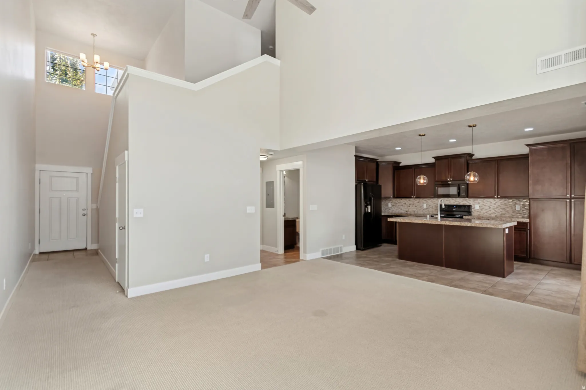 Vaulted ceiling with a ceiling fan, kitchen featuring dark wood cabinetry, a central island with a light-toned countertop, and stainless steel appliances