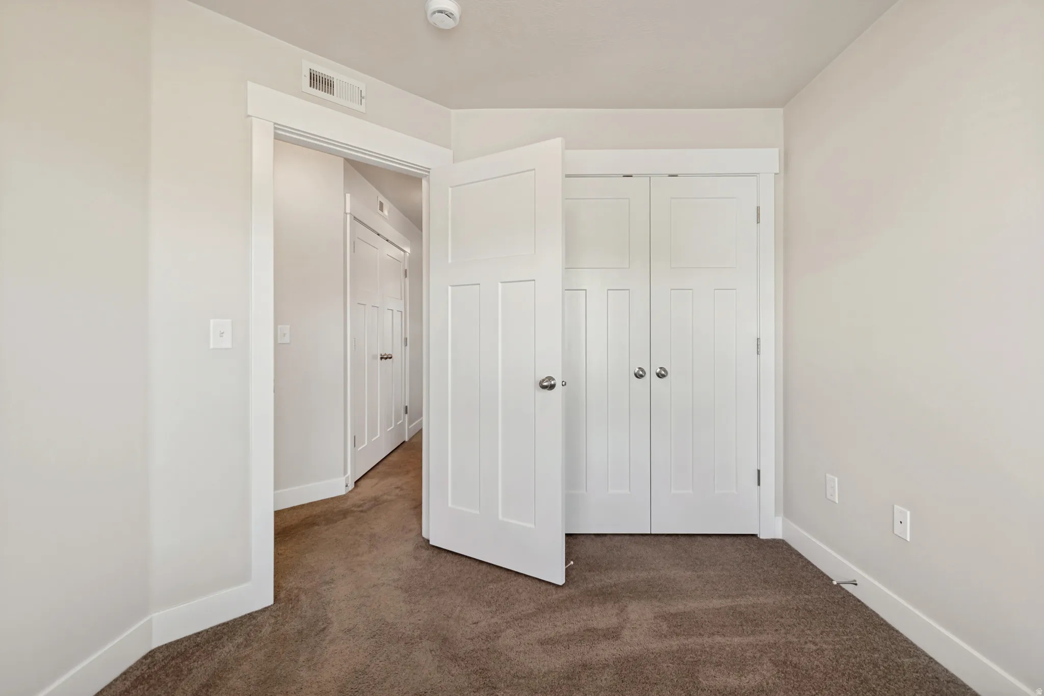 Neutral wall paint, plush carpet flooring, white trim, and white paneled doors