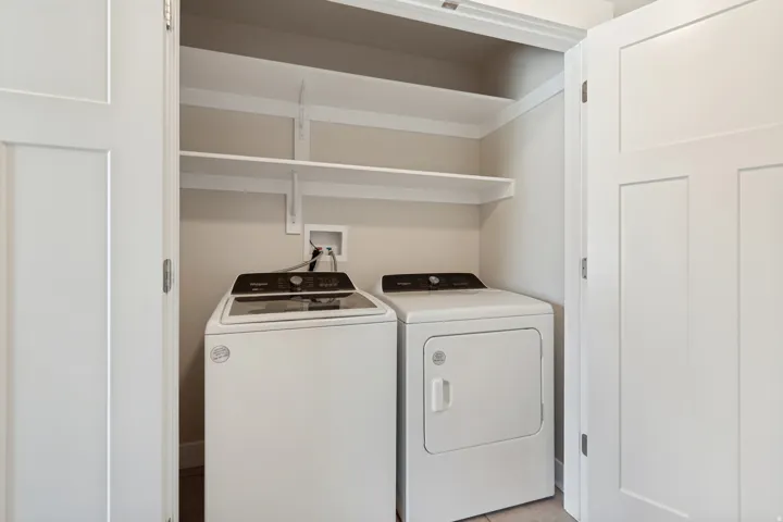 Integrated laundry area featuring white panel doors and upper shelving