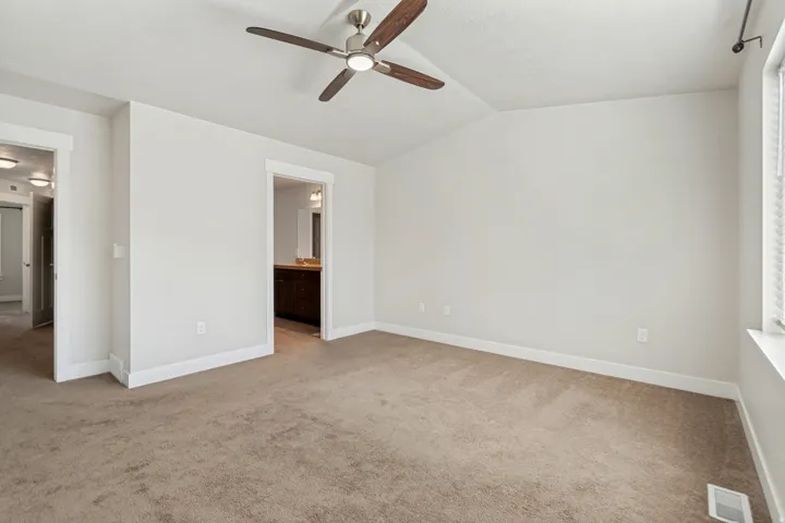 Spacious room featuring neutral carpet flooring, a ceiling fan with integrated lighting, and white trim