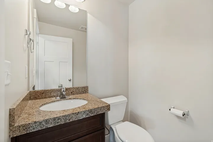 Vanity with an undermount sink, granite countertop, chrome faucet, and dark wood-finish cabinetry