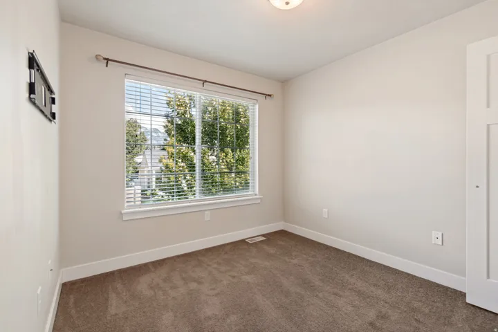 Wall-to-wall carpeting, large window with blinds, surface-mounted light fixture, white interior door, and neutral wall paint