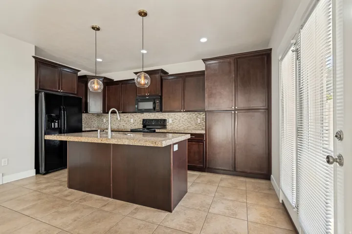 Kitchen with dark wood cabinetry, a central island with a light-toned countertop, and recessed lighting