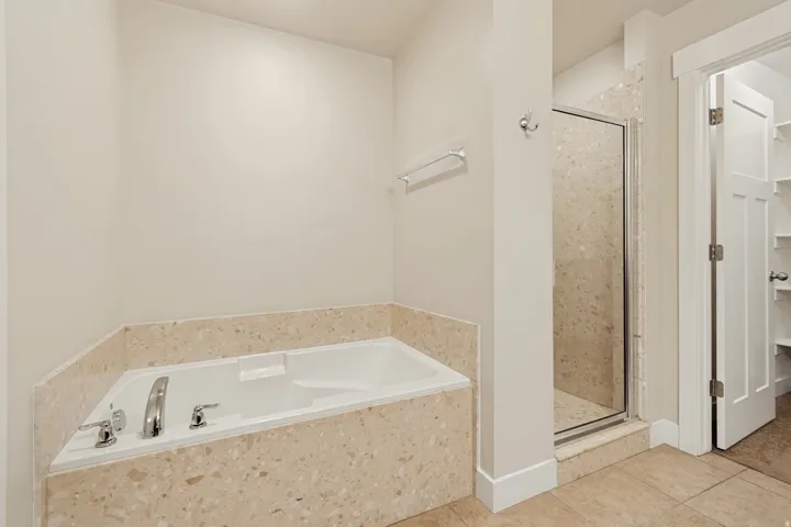 Built-in soaking tub with a tiled surround, chrome fixtures, and a glass-enclosed shower with tiled walls