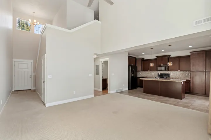 Vaulted ceiling with a ceiling fan, kitchen featuring dark wood cabinetry, a central island with a light-toned countertop, and stainless steel appliances