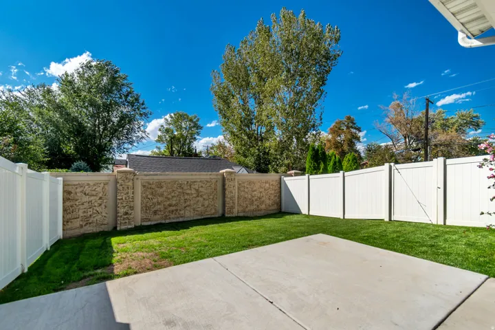 Private backyard featuring a concrete patio, manicured lawn, and perimeter fencing