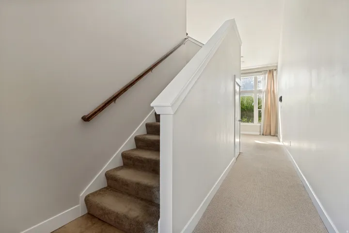 Carpeted staircase with wood handrail